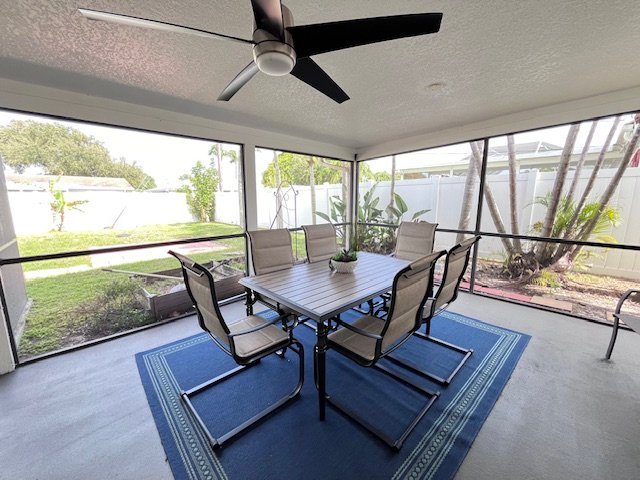 Screened patio with a table, chairs and a ceiling fan at a Serenity Living home